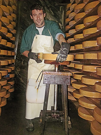 il casaro pulisce la forma di fontina nella grotta delle fontine a La Thuile