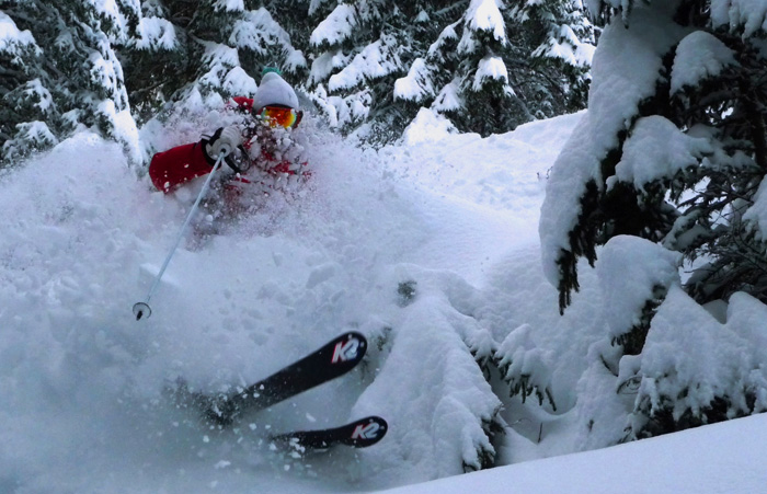 foto di un freerider nel bosco in una nuvola di neve