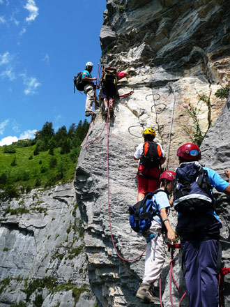 vacanze estive in montagna cordata ragazzi in parete con la guida alpina